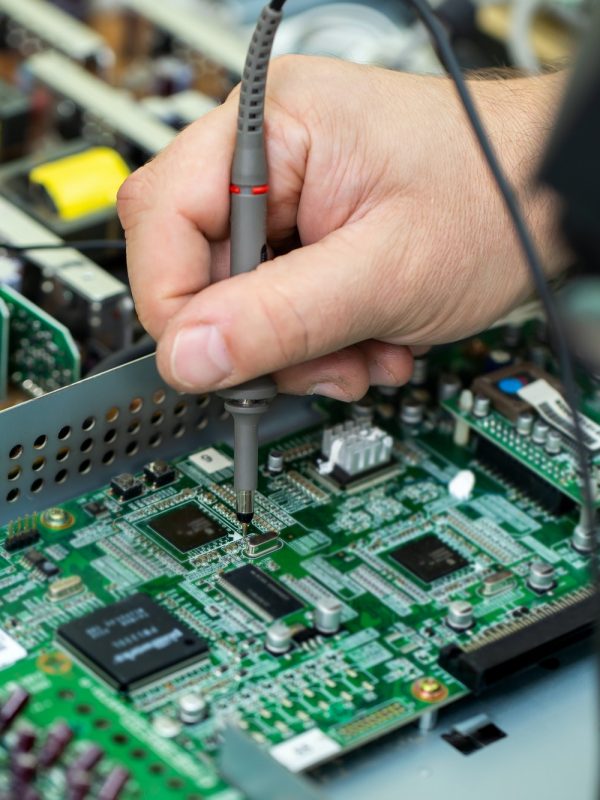 An electrician measures the voltage while repairing an LSD TV in a service center.